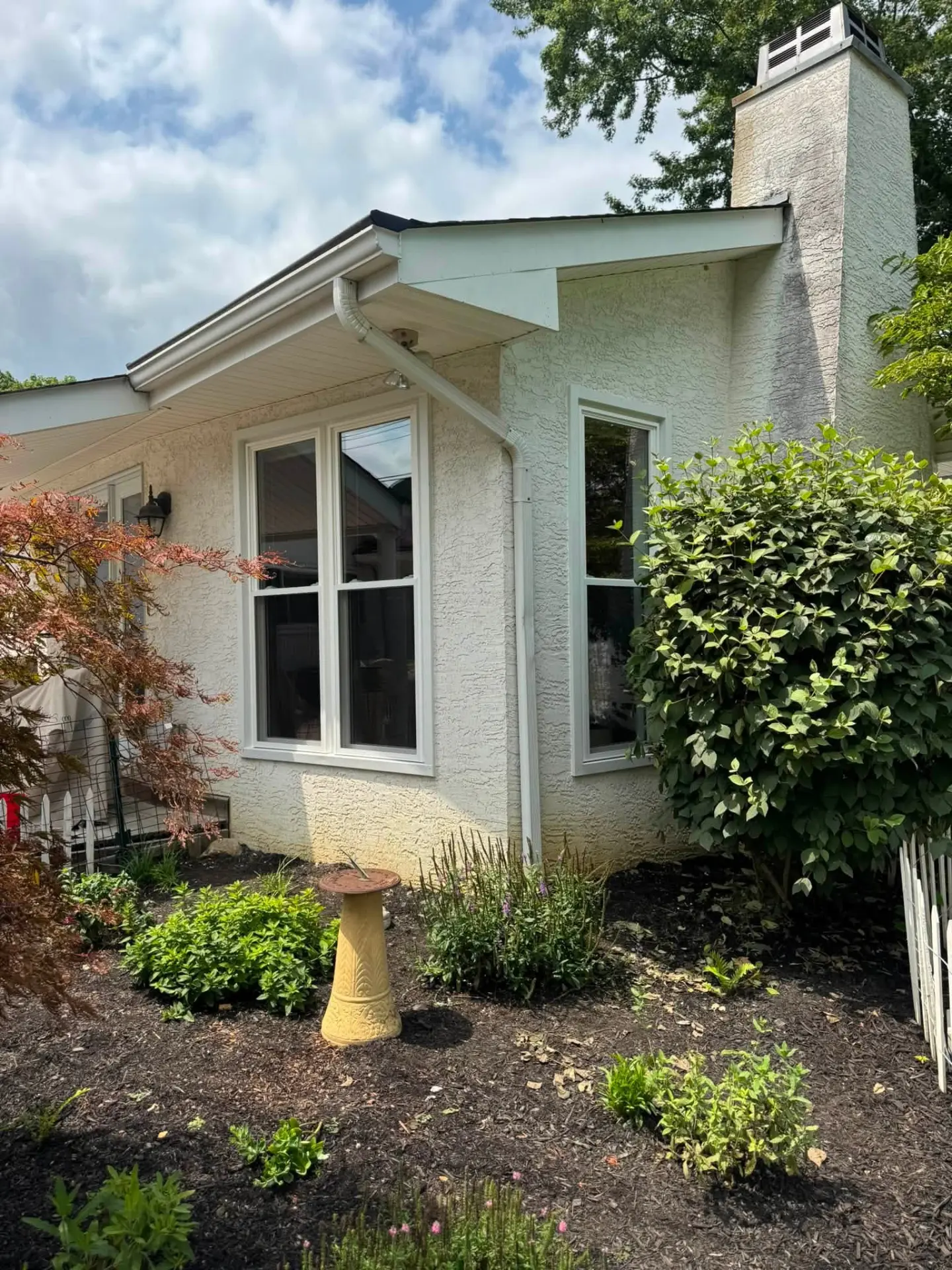 Exterior of a renovated light stucco home with fresh landscaping