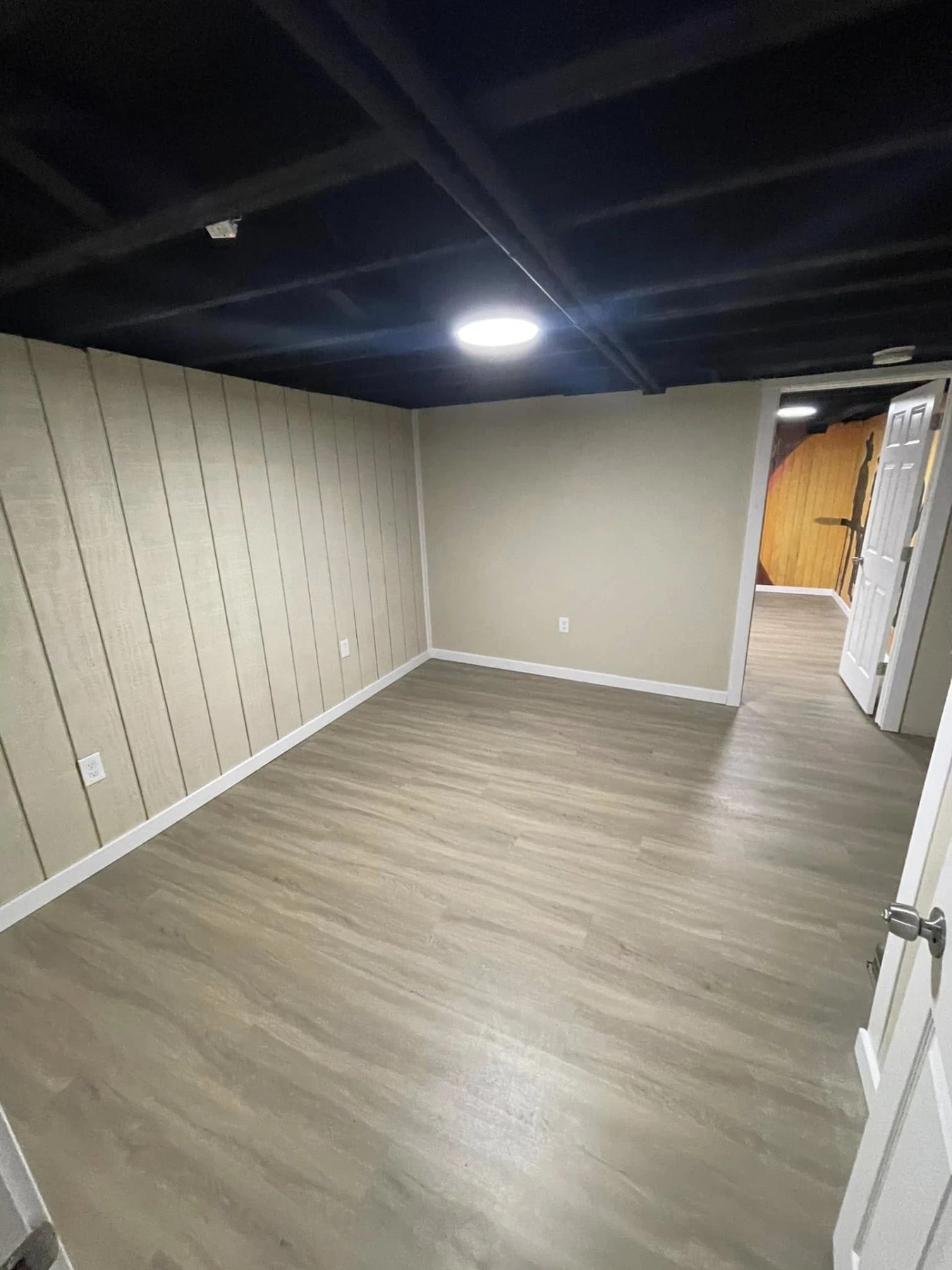 Finished basement room with new plank flooring, trim and painted ceiling