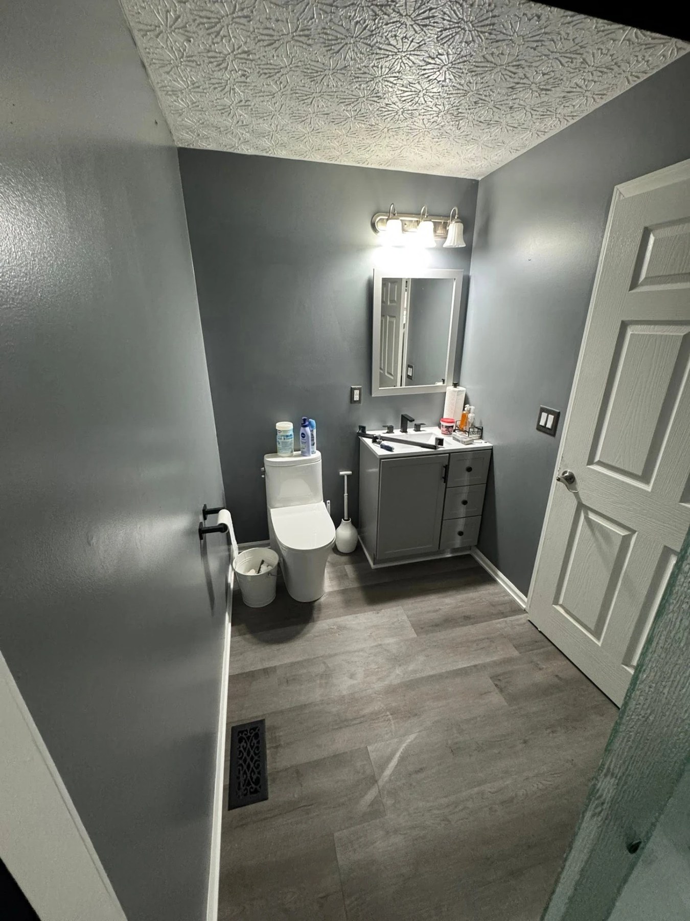 Renovated bathroom with grey vanity, new fixtures and plank flooring